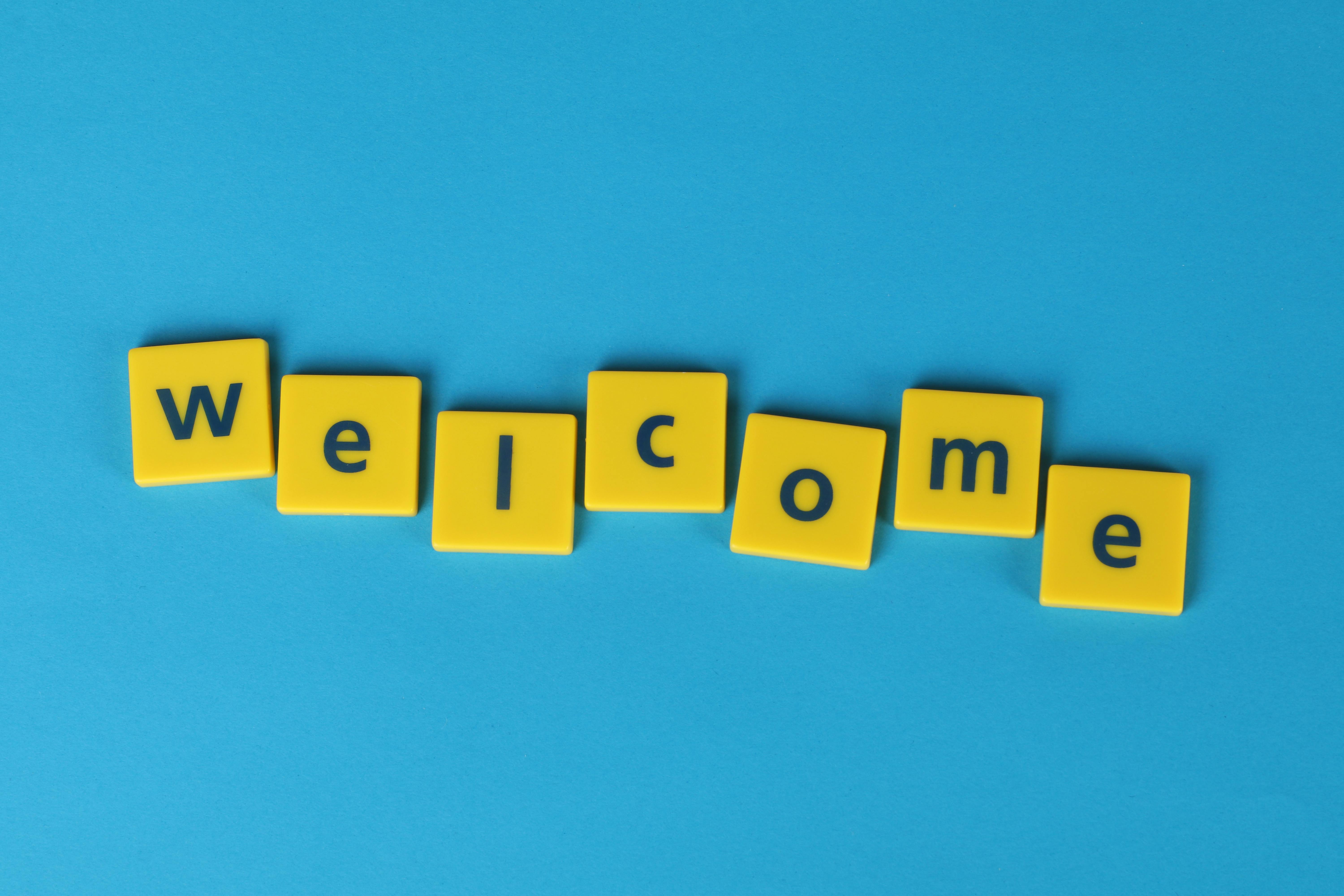 Welcome is written, each letter in on a  yellow tile on a blue background.
