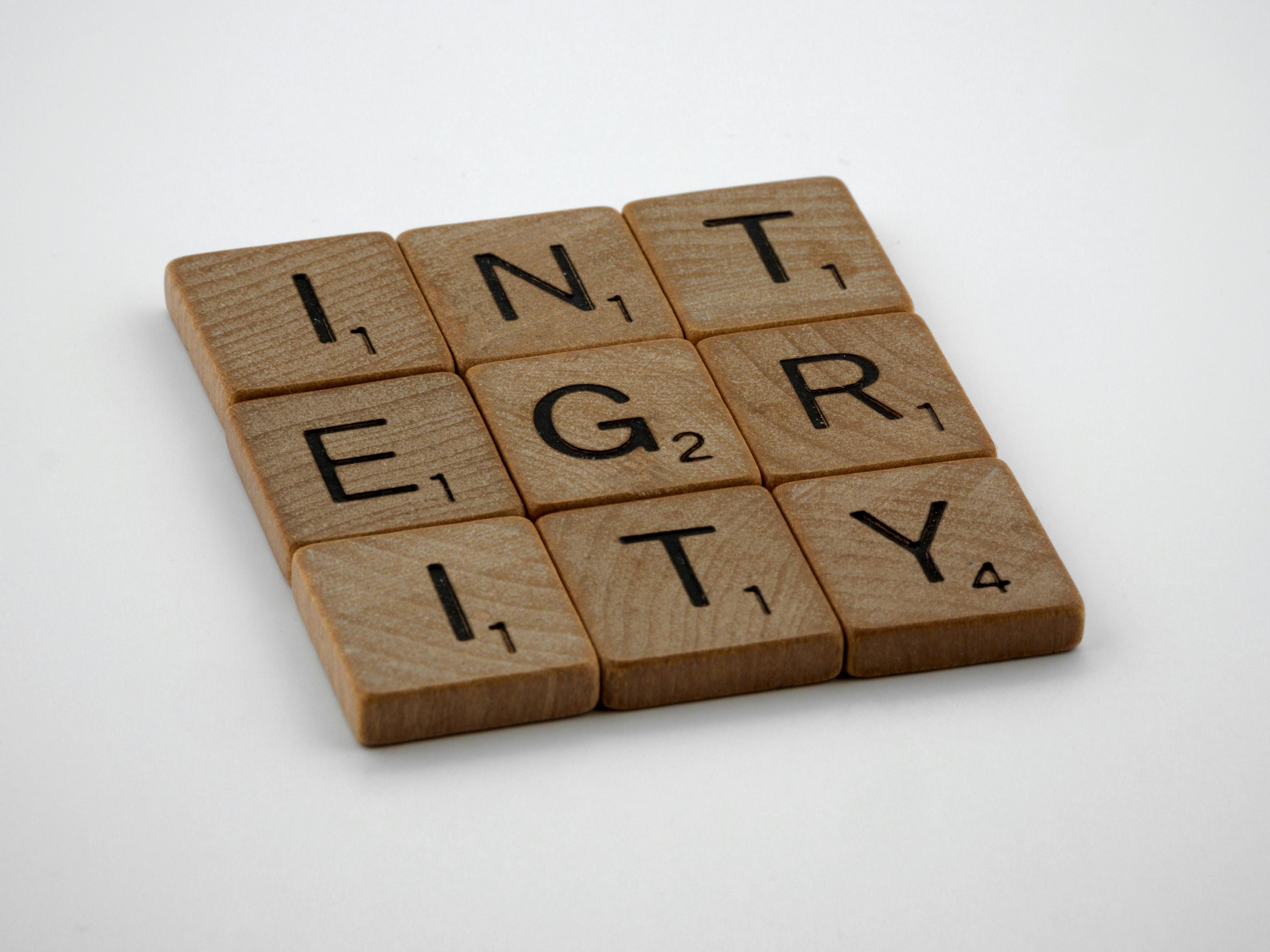 Integrity in written. Each letter is on a tile and they have been laid out in the shape of a square.