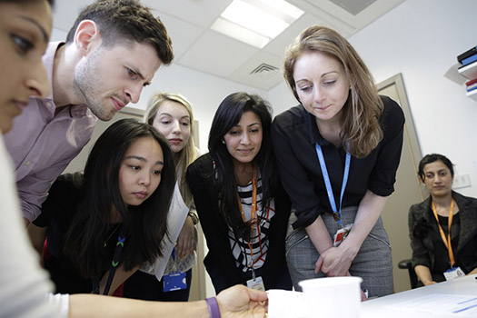 Students and teachers hovering over a document on a table